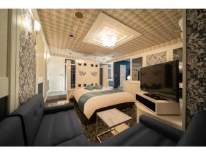 大垣Royal Hotel Uohachi Bettei - Vacation STAY 81417的一间卧室配有一张床、一台电视和一张沙发