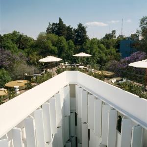 墨西哥城Condesa df, Mexico City, a Member of Design Hotels的花园内带桌子和遮阳伞的阳台