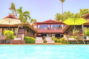 班拉克海滩爱侣湾别墅酒店的游泳池旁带椅子和遮阳伞的房子