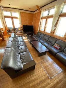 立山町Tengudaira Mountain Lodge的大型客厅配有黑色真皮沙发