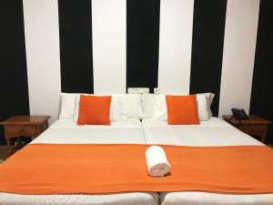 卡拉斯帕拉Hotel Argos的一张带橙色和白色枕头的大床