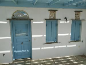 基奥尼亚Villa Ioanna Tinos的一面墙,有两扇蓝色的门,两扇窗户