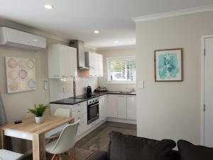 罗托鲁瓦Rose Apartments Unit 1 Central Rotorua-Accommodation&Spa的厨房配有白色橱柜和木桌