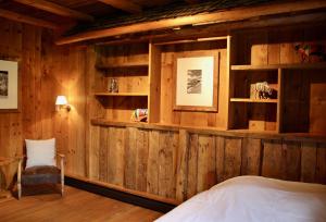 南达Gîte de Planchouet的卧室设有木墙、一张床和椅子