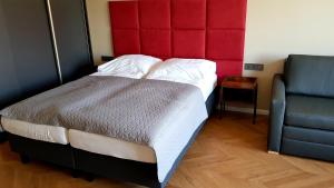 弗罗茨瓦夫Apartament Wrocław Marina nad Odrą 29的一间卧室配有一张带红色床头板和椅子的床