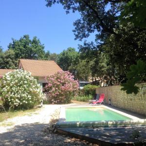 Arpaillargues-et-AureillacVilla de 3 chambres avec piscine privee jardin clos et wifi a Arpaillargues et Aureillac的一个带红色椅子的庭院内的游泳池