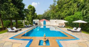 萨瓦伊马多普尔Sawai Madhopur Lodge - IHCL SeleQtions的一个带躺椅和遮阳伞的游泳池