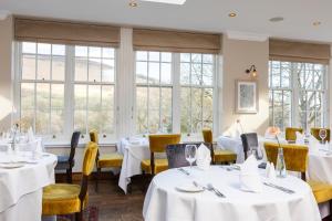 霍普卢斯希尔水疗酒店的餐厅设有白色的桌子和黄色的椅子以及窗户。