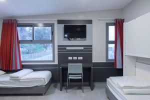 海法HI - Haifa Hostel的一间卧室配有书桌、电视和椅子