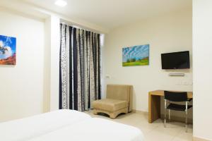 Poriyya海珀瑞亚旅舍的一间卧室配有一张床、一张书桌和一台电视。