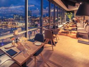 阿姆斯特丹阿姆斯特丹斯劳特戴克站美居酒店的餐厅设有桌椅和大窗户。