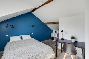 枫丹白露Charme et Design à Proximité du Château的一间设有蓝色墙壁、一张床和一张书桌的卧室