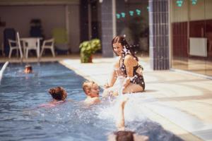 巴拉顿菲赖德Danubius Hotel Annabella的一名女子和两名儿童在游泳池玩耍