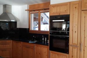 奥瓦伦纳茨Chalet La Marendaz的厨房配有木制橱柜和黑炉灶烤箱。