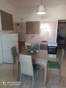 托雷桑塔萨宾娜Casa al mare的厨房配有桌椅和白色冰箱。