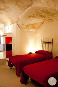 马泰拉Da Zia Lalla的一间卧室,在房间内配有两张红色的床