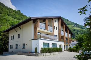 丘萨Residence Laitacherhof - Modern eingerichtete Apartments in der Nähe vom Zentrum von Klausen mit Aussenpool und Sauna的一座白色的大建筑,设有木屋顶