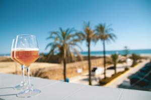 萨阿拉德洛斯阿图内斯Hotel Avenida Playa的坐在海滩旁的桌子上喝一杯啤酒