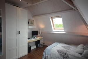 海牙De Pimpelmees的一间卧室配有一张床、一张书桌和一个窗户。