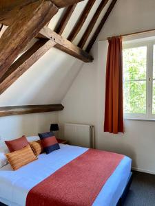 布鲁日阿多纳斯酒店的一间卧室配有一张带红色毯子的床和窗户。