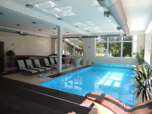 阿普苏奇耶姆斯Hotel SPA Arkadia的一座带椅子和桌子的建筑中的游泳池