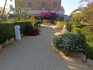 梅萨涅Agriturismo Tenuta Mazzetta的一座种植了灌木和鲜花的花园以及一座建筑