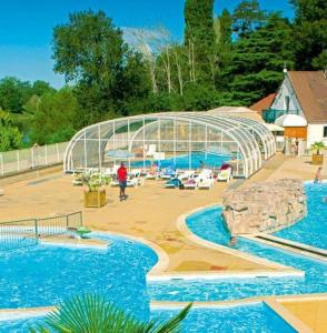 特罗格Bungalow de 3 chambres avec piscine partagee et terrasse amenagee a Trogues的一个带两个游泳池和玻璃屋的游泳池