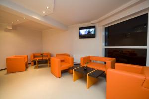 阿普苏奇耶姆斯Hotel SPA Arkadia的一间配备有橙色椅子和平面电视的等候室