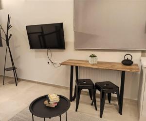 沃洛斯Stylish Ground Floor Maisonette的教室,配有桌子、两个凳子和屏幕