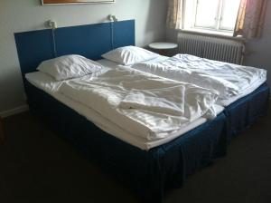 伦讷德特里列酒店的一张带蓝色床头板、白色床单和枕头的床