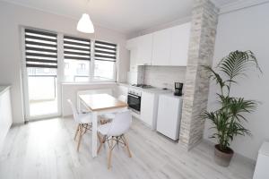 锡比乌Apartament 2 camere Anto的厨房配有白色橱柜和桌椅