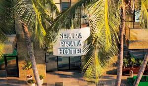 福塔莱萨斯汝普莱亚酒店的一座建筑前有棕榈树的酒店标志