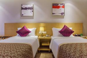 重庆重庆静时文化酒店的两张位于酒店客房的床铺,配有紫色枕头