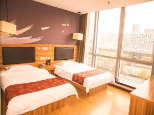 郑州尚客优酒店河南郑州郑东新区东站店的酒店客房设有两张床和大窗户。