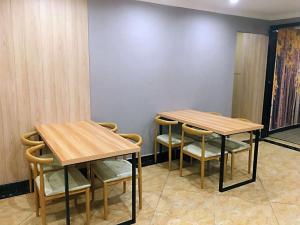 渝北骏怡连锁重庆渝北区江北国际机场空港广场店 的墙上的房间里设有两张木桌和椅子