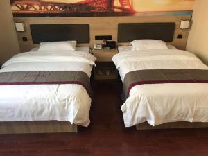 南京尚客优酒店江苏南京江宁区陶吴店的配有白色床单的酒店客房内的两张床