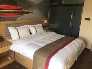 Kaiba尚客优酒店青海海西州乌兰县兴海商业街店的一张配有白色床单和枕头的大床