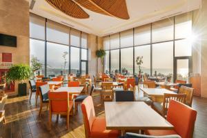 岘港Sala Danang Beach Hotel的餐厅设有桌椅和大窗户。