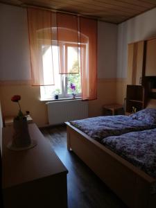 格拉德贝克Ferienwohnung Gladbeck-Rohde的一间卧室设有一张床和一个鲜花窗口