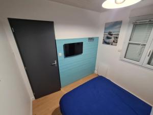 莱萨布勒-多洛讷Maison 2 Chambres Parking Linge de lit fourni的一间设有蓝色门和电视的房间