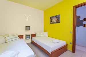 基拉奇尼Gerakina Skala Holiday Houses的黄色墙壁客房的两张床