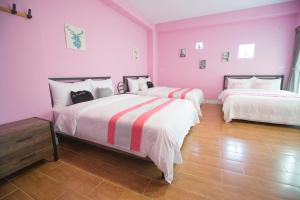 马公綠光海岸民宿的配有粉红色墙壁和木地板的客房内的两张床
