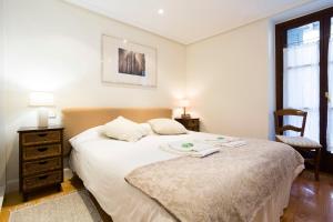 宏达瑞比亚Txoriak - Basquenjoy的卧室配有一张白色大床和一把椅子