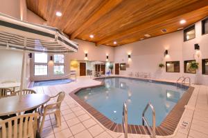 米切尔Kelly Inn and Suites Mitchell的游泳池位于酒店客房内,配有桌椅