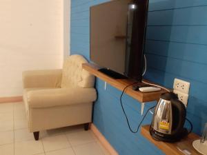 曼谷Infinite Hotel的一个带椅子和桌子上的电视的房间