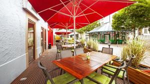 米赫拉克尔施费斯艾克酒店的庭院里配有一张木桌和椅子及红伞