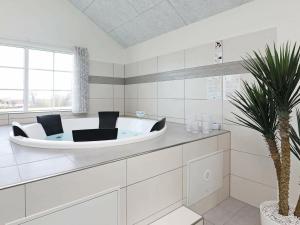 Frørup26 person holiday home in Fr rup的白色的浴室设有浴缸和棕榈树