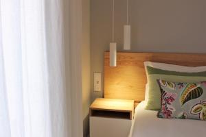法鲁Cardeal Suites & Apartments的靠窗的一张带木制床头板的床