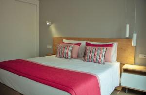 法鲁Cardeal Suites & Apartments的卧室配有一张带粉红色枕头的大床