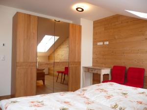 普夫龙滕Alpenstern Ferienwohnung的一间卧室配有一张床和一张带红色椅子的桌子